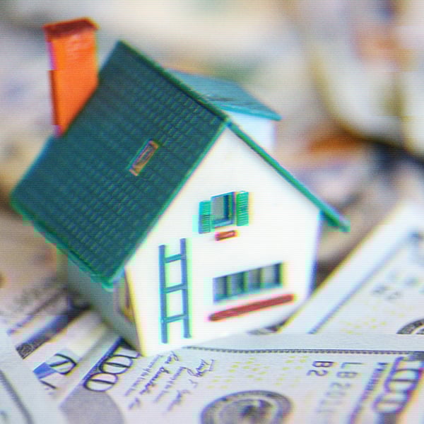 A toy house surrounded by $100 bills.