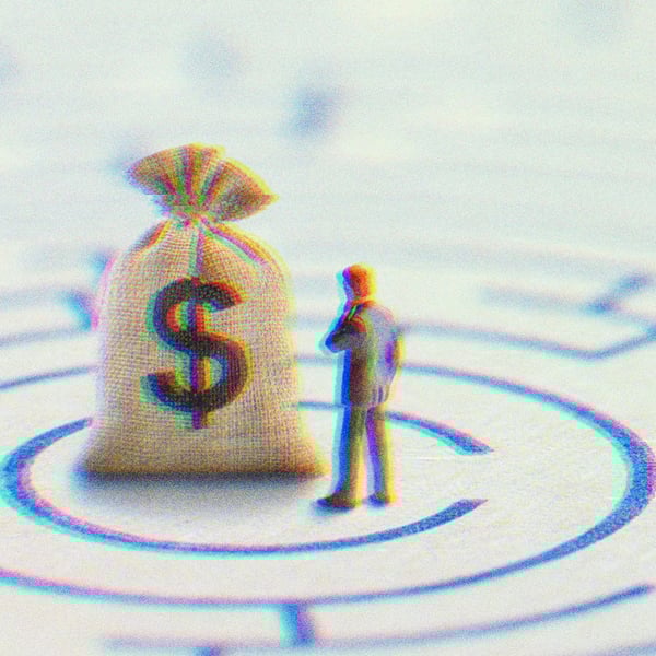 A miniature figurine looking at a sack with a dollar bill on it.
