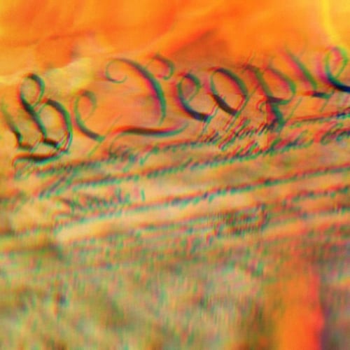 Close up on US Constitution showing the words The People; the Constitution is engulfed in flames.