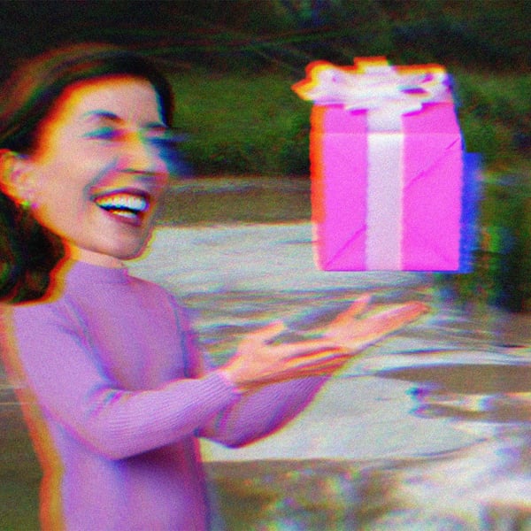 Kathy Hochul laughing and giving a gift. The background is a mudboil in the Tully Valley.