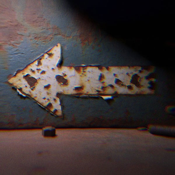 A grungy metal arrow pointing left