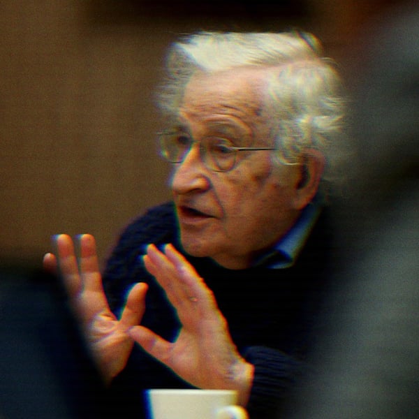 Noam Chomsky speaking, his hands raised..