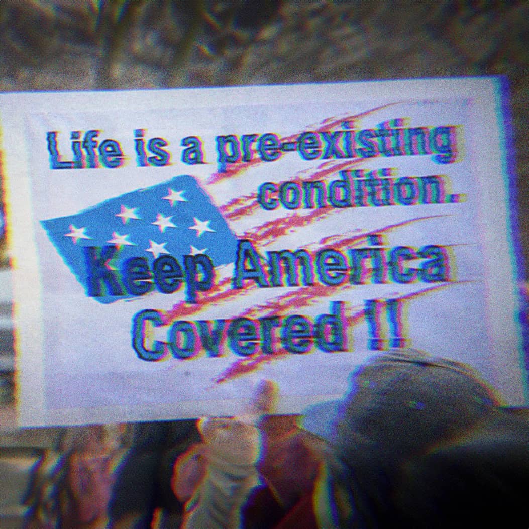 Protest sign that says Life is a pre-existing condition. Keep America covered.