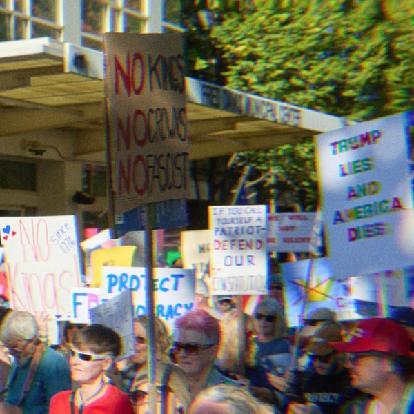 Protestors in California at No Kings, holding signs that read ‘We the people means everyone,’ 'No Kings, No Crowns, No Fascist,’ ‘Trump Lies and America Dies,’ and more out of view.