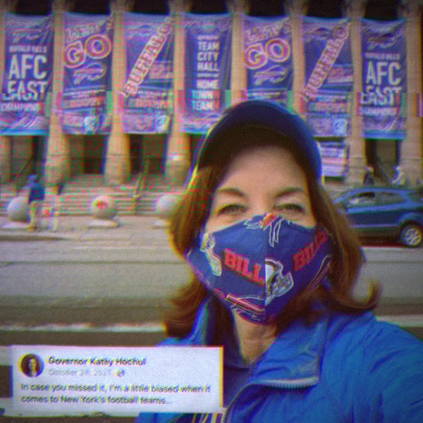 Selfie of Governor Kathy Hochul in front of the Buffalo Bills Stadium, wearing a Buffalo Bills mask. Text on the image says,