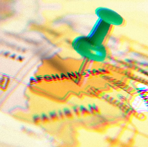 Green pushpin pressed into a map, the pin is sticking into Afghanistan.