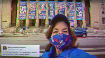 Selfie of Governor Kathy Hochul in front of the Buffalo Bills Stadium, wearing a Buffalo Bills mask. Text on the image says, 