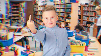 Young student in an art classroom giving the middle finger.