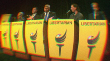 Candidates standing at yellow podiums that have the Libertarian logo on them. 