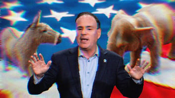 Jay Jacobs standing mid-speech; the background is an American flag and an elephant and a donkey.