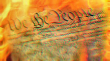 Close up on the U.S. Constitution, showing the words 'The People.' The Constitution is engulfed in flames.