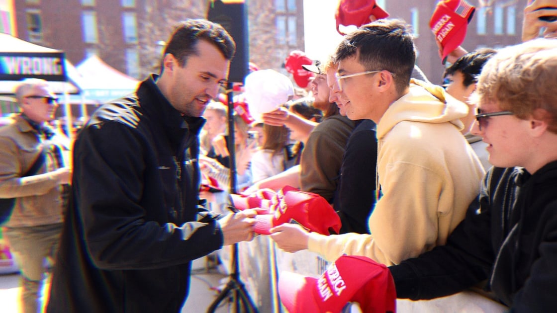 Charlie Kirk signing red MAGA hats on an April stop of his American Comeback Tour