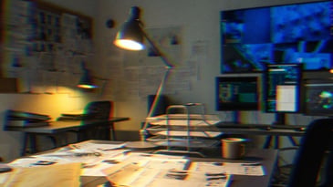 An FBI-type room with surveillance footage and documents on the table.