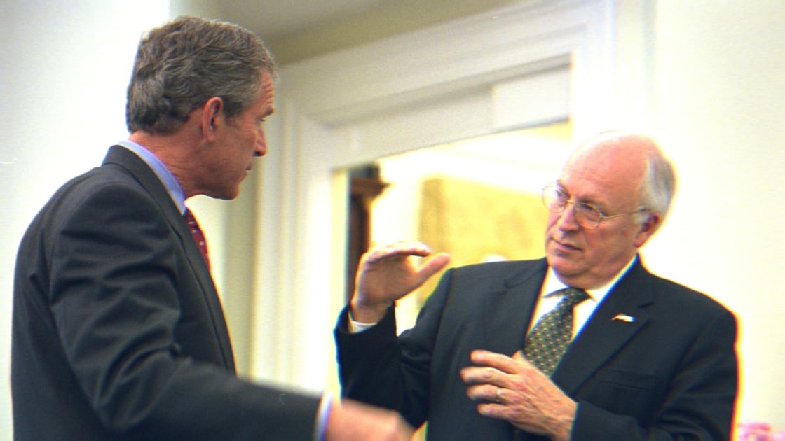 George W. Bush and Dick Cheney in conversation, 2002. Cheney is explaining something with his hands.