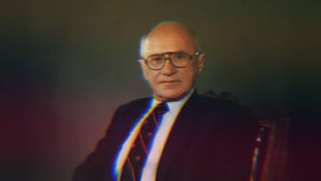 Milton Friedman sitting in a chair.