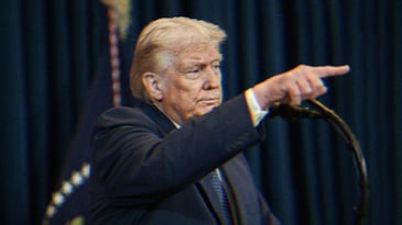 Trump speaking at a podium and pointing.