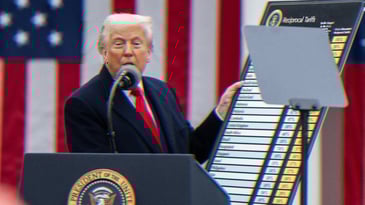 Trump standing at a podium speaking into a microphone holding a poster titled Reciprocal Tariffs.