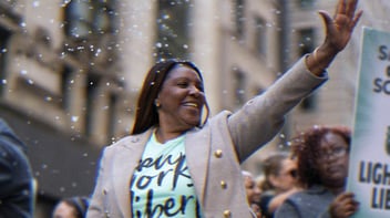 Letitia James celebrating the win of The Liberty in 2024. She is wearing a Liberty t-shirt, smiling and waving.