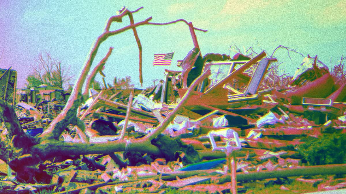 A destroyed home with an American flag still standing.