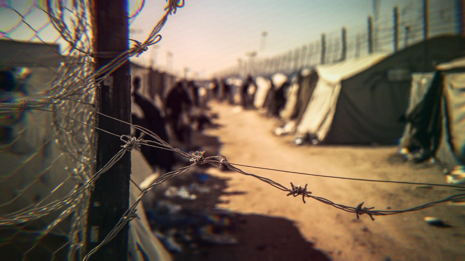 Barbed wire surrounding an encampment at the border.
