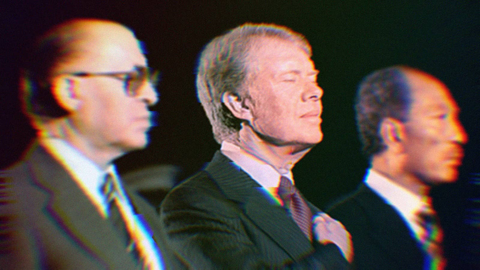 Begin, Carter, and Sadat at a ceremony in September, 1978. Carter is in focus and has his hand over his heart with his eyes closed.