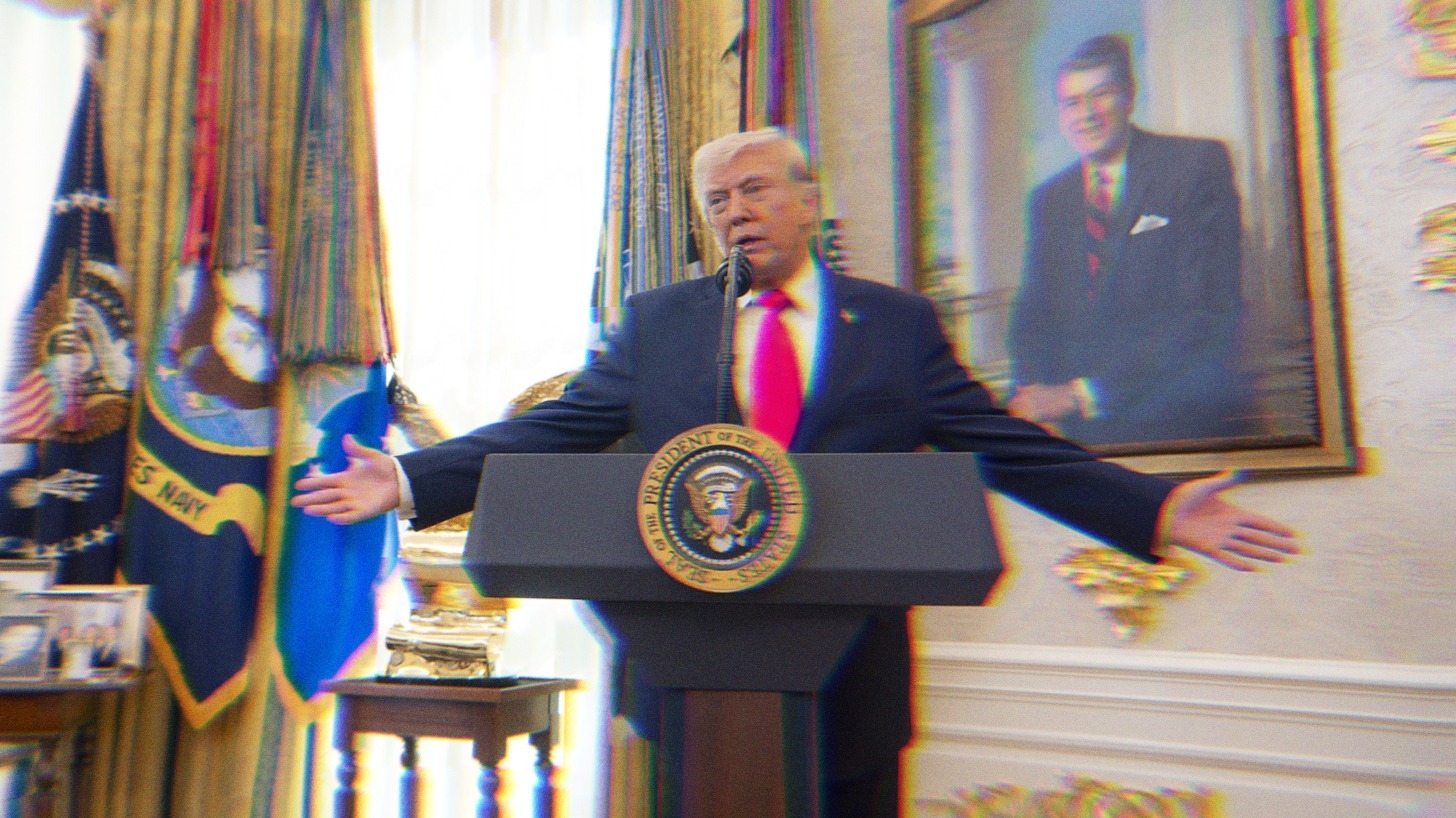 Donald Trump standing at a podium in the Oval Office with his arms outstretched, he is mid speech.