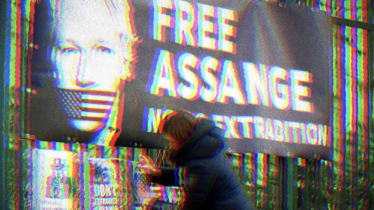 Glitchy photo of a banner with a photo of Julian Assange with American Flag tape over his mouth. Banner text says, ‘Free Assange. No U.S. Extradition.’ Below the banner a woman is adding another pro-Assange poster.