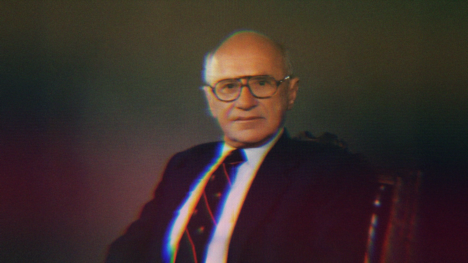 Milton Friedman sitting in a chair.