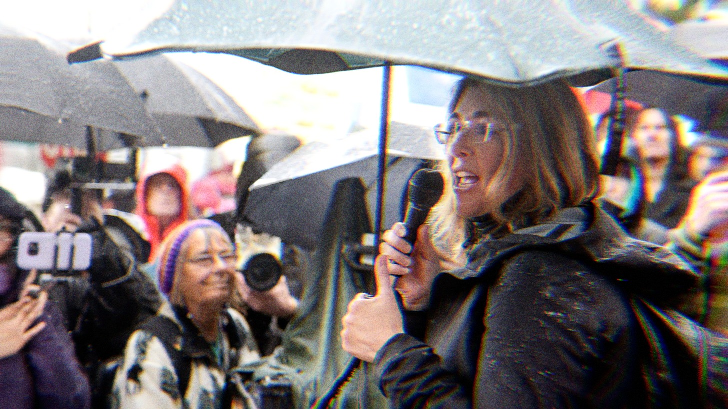 Naomi Klein speaking at an event in the rain.